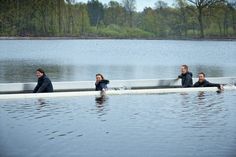 four people are sitting on a long boat in the middle of a body of water