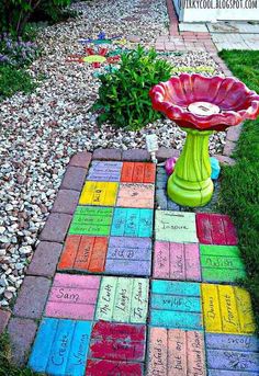 a garden with colorful bricks and flowers on the ground, in front of a sign that says