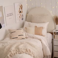 a bed with white sheets and pillows in a bedroom next to pictures on the wall