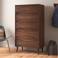 a wooden chest of drawers next to a blue chair