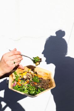 a person is holding a spoon over a bowl of food