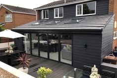 a black house with an outdoor patio and dining area in the back ground, surrounded by brick buildings