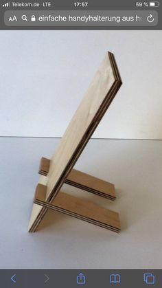 a wooden object sitting on top of a white table next to a cell phone holder