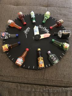 a clock made out of various bottles on a couch with the words happy birthday written on it