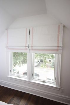 a bedroom with two windows that have roman shades on them