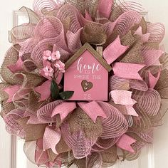 a pink and brown mesh wreath with a birdhouse on it that says home is where the heart is