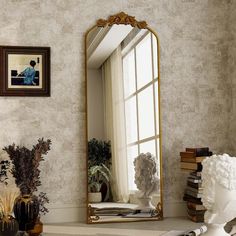 a mirror sitting on top of a table next to a vase and potted plant