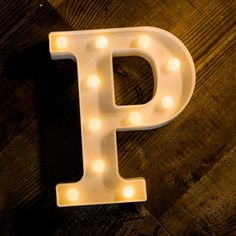 the letter p is lit up with light bulbs on a wooden surface in front of it