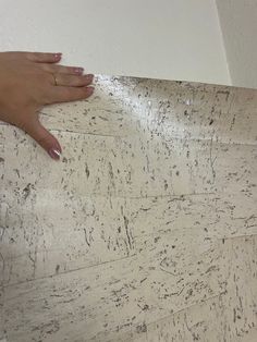 a person's hand on top of a wooden floor with white paint and scratches