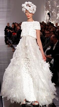 a woman is walking down the runway in a white dress