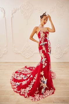 a woman in a red dress with flowers on it and her hands behind her head