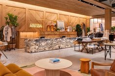 the interior of a clothing store with wooden walls and tables, chairs, and couches