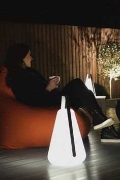 a woman is sitting on a bean bag chair with a remote control in her hand