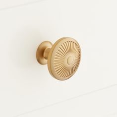 an antique brass door handle on a white painted cabinet with wood grained edges and a sunburst design