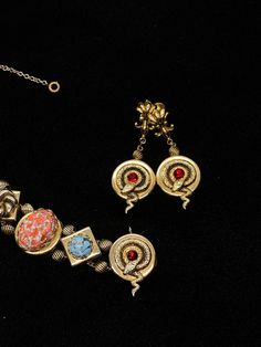 "Very little information can be found on the PIK MGK NYC jewelry makers but they did produce an exceptional art glass and serpent slide bracelet and earrings with this set; the dangle screw back earrings features the curled serpent and ruby red stone which matches one of the link on the bracelet and are 2\" long; the bracelet is 7\" long and 3/4\" wide with spring safety chain; each of the nine embossed links feature a different design and stone; the stone colors are amazing; ruby red, speckled Art Deco Clip-on Jewelry For Formal Occasions, Clip-on Art Deco Jewelry For Formal Occasions, Formal Art Deco Clip-on Jewelry, Fine Jewelry Bracelet With Cabochon, Formal Metal Clip-on Jewelry, Metal Clip-on Round Jewelry, Metal Clip-on Dangle Jewelry, Costume Jewelry Sets With Matching Round Earrings, Metal Clip-on Dangle Earrings