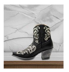 Step into a blend of traditional Western style and modern flair with the Women's Silina Western Medium Sizes Booties. Crafted with a premium leather upper, these stunning black booties feature a classic snip toe design that adds a touch of elegance to any outfit.  The solid black exterior is beautifully accented with intricate tan embroidery, eye-catching gold glitter inlays, and gold studded details throughout, making these booties perfect for those who love to stand out in a crowd. The pull tab combined with internal zippers ensures easy on-and-off wear, while providing a snug fit for all-day comfort. Designed with a Western heel, these booties offer a stylish lift while still maintaining stability. The leather outsole is complemented by a rubber heel cap, ensuring durability and tractio Western Booties, Heel Caps, Cowboy Western, Black Exterior, Western Cowboy Boots, Rubber Heels, Toe Designs, Atlanta Ga, Black Booties