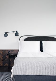 a bed with white sheets and black headboard