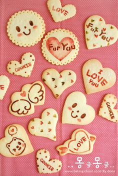 some heart shaped cookies are arranged on a pink tablecloth with words written in different languages