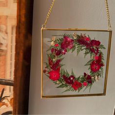 a mirror hanging on a wall with flowers in the middle and greenery around it