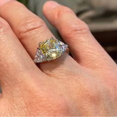 a woman's hand with a yellow diamond ring on it