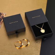 two gold rings and a necklace sitting on a table next to a box that says boyang