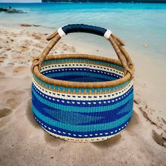 a blue and white basket sitting on top of a sandy beach