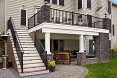 a patio with stairs leading up to the second floor and an outdoor living area on the other side