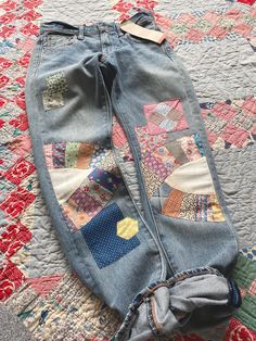 an old pair of jeans with patchwork on them laying on top of a quilt