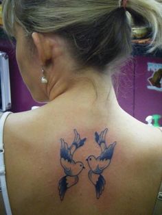 a woman's back tattoo with two birds on her left shoulder and the word love written in blue ink