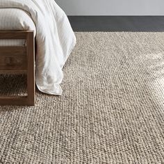 a bed sitting on top of a carpeted floor next to a wooden headboard