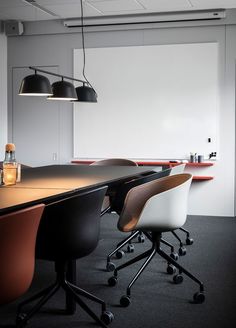 an empty conference room with black and white chairs, wooden tables and hanging light fixtures