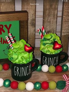 two cups filled with green veggies and candy canes on top of a table