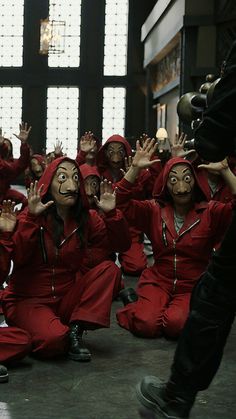 several people in red outfits sitting on the floor with their hands up to their faces