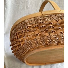 a basket made out of wood and woven with holes in the middle, sitting on a white sheet