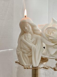 a candle that is sitting on a table with some flowers in front of the candle