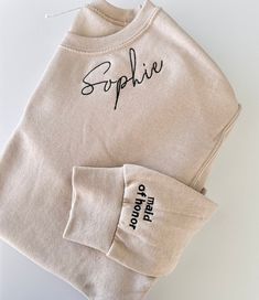 two personalized sweatshirts with embroidered name on the front and back, sitting next to each other