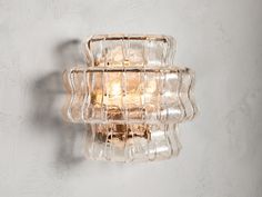 a glass light fixture mounted on the side of a wall next to a white wall