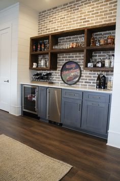 a kitchen with wooden floors and brick wall behind the counter top is an oven, dishwasher, and refrigerator