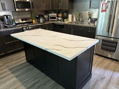 a kitchen with stainless steel appliances and granite counter tops, along with an island in the middle