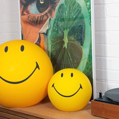 two yellow balls sitting on top of a wooden table next to a painting and record player