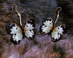 three pairs of beaded butterfly earrings sitting on top of a fur covered animal skin