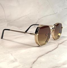 These aviator sunglasses feature a vintage 70s-inspired design with an octagonal shape. The lenses have a stylish brown ombre tint, perfectly complemented by a sleek gold metal frame. Suitable for both men and women, these shades add a retro flair to any look while offering classic pilot style. NOS Deadstock Made in Europe FIT INFORMATION  55mm Eye Size 22mm Bridge 145mm Temple/Arm Width 5 Inches Height 1 3/4 Inches Luxury Elegant Men's Aviator Sunglasses, Tan Luxury Sunglasses, Luxury Gold Aviator Sunglasses With Metal Frame, Luxury Vintage Gold Aviator Sunglasses, Gold Retro Aviator Sunglasses With Gradient Lenses, Retro Gold Aviator Sunglasses With Gradient Lenses, Retro Aviator Sunglasses With Metal Frame, Retro Gold Shield Sunglasses With Uv Protection, Retro Gold Shield Sunglasses With Gradient Lenses