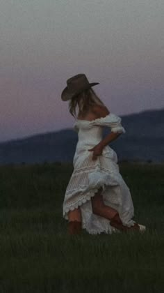 a woman in a white dress and cowboy hat