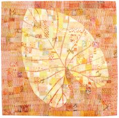 an orange and yellow quilt with leaves on it's back side, in the middle of