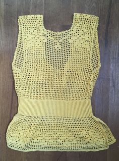 a yellow knitted top sitting on top of a wooden floor