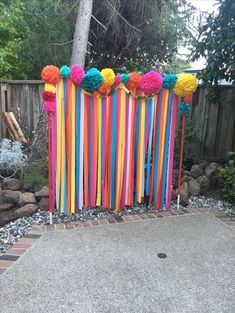 colorful paper pom poms and streamers are on the side of a fence