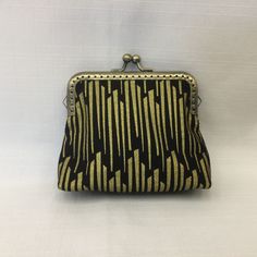 "This bright and elegant change purse is designed in gold metallic bars on a black background. Item can also be used as a small cosmetics bag, key holder, medication pouch, credit card holder, or an organizer for any small items in your handbag. Square shaped bag has a gold filigree metal purse frame with a ball clasp closure. Purse frame is sewn in with clear nylon fishing line to form invisible stitching on the outside. Outside fabric is cotton print, lining is solid black cotton fabric and it