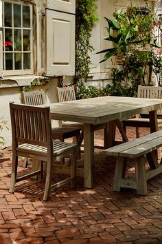 a wooden table and chairs sitting on a brick patio