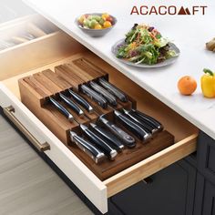 an open drawer in a kitchen with knives and salad on the counter next to it