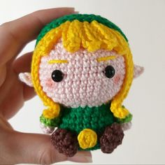 a small crocheted doll with blonde hair and black eyes holding it in her hand